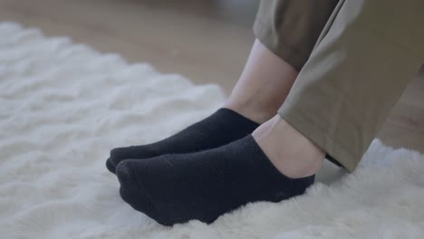 person's feet in black socks resting on a white fluffy rug
