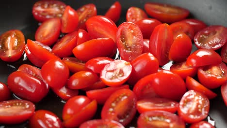 close up shot of heated pan with olive oil and putting halved cherry tomatoes in