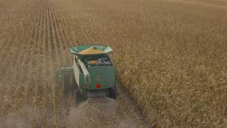 a midwest farmer harvesting a corn field with a combine, tractor, and auger wagon