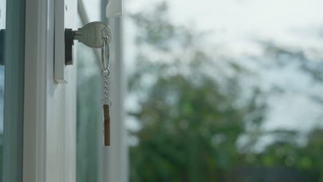 the house key for unlocking a new house is plugged into the door. the sell house keychain was moving as the wind blew