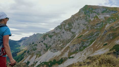 young tourist backpacker woman taking a panorama photo of the mountains with her phone, wide shot