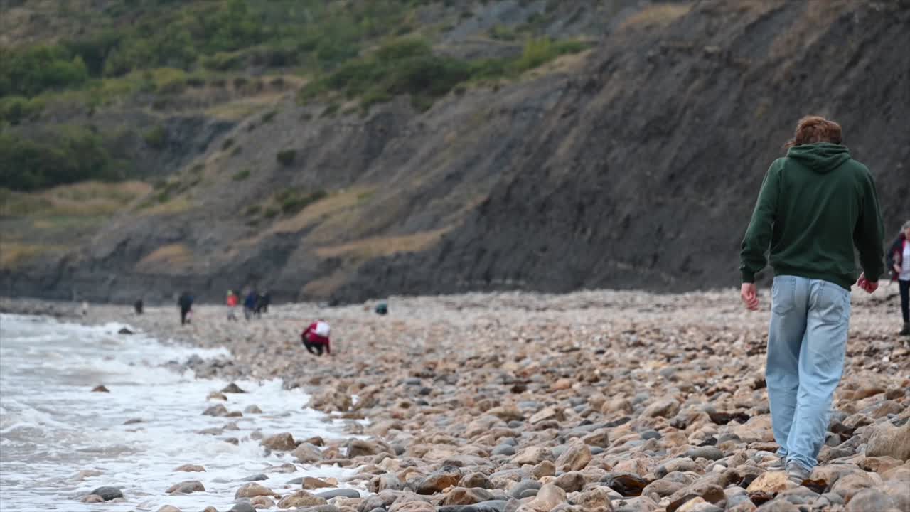 바위가 많은 해변을 걷는 한 사람