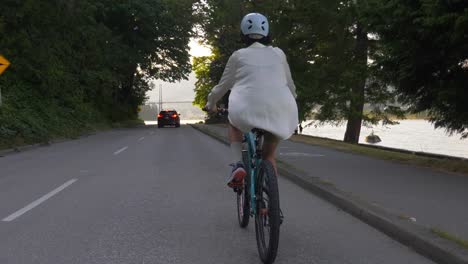 Mujer-Ciclista-Con-Casco-A-Través-De-La-Carretera-Pavimentada