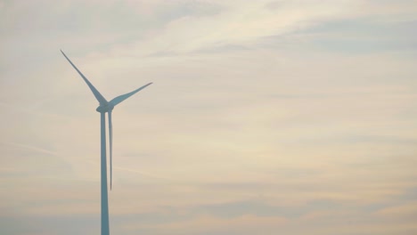 Windmill-with-background-filled-with-clouds-during-dusk,-seen-from-moving-train