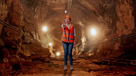 full body of asian female engineer with safety helmet disapproving with no hand sign in underground mine tunnel