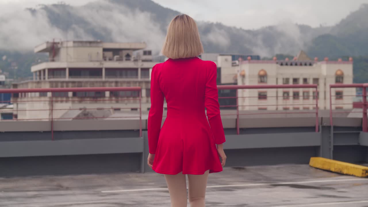 바쁜 도시의 지붕은 짧은 빨간 드레스를 입고 걸어가는 젊은 히스패닉 소녀의 무대가 됩니다.