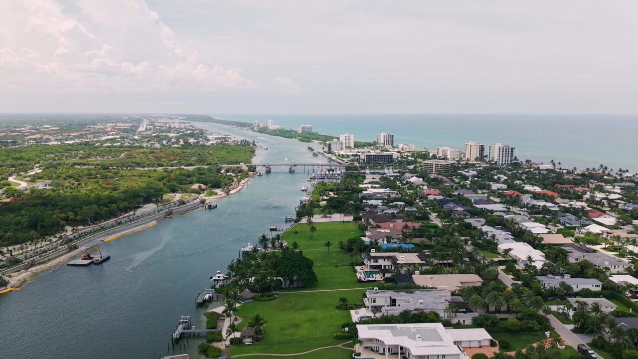 Corso d'acqua di Jupiter Inlet con ponte, case fronte mare e costa, panoramica aerea da drone del fiume Indian River, Florida, USA