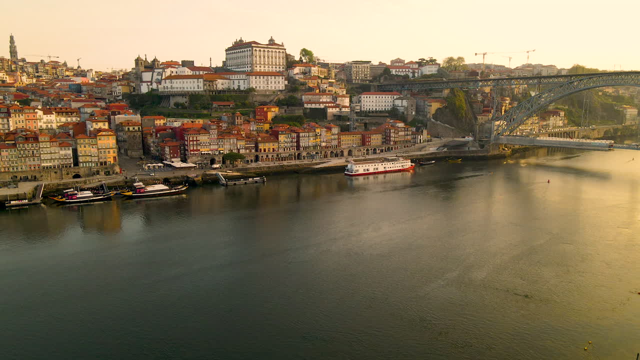 Tomada de drone descendente do Rio Douro e da paisagem urbana histórica do Porto ao pôr do sol.