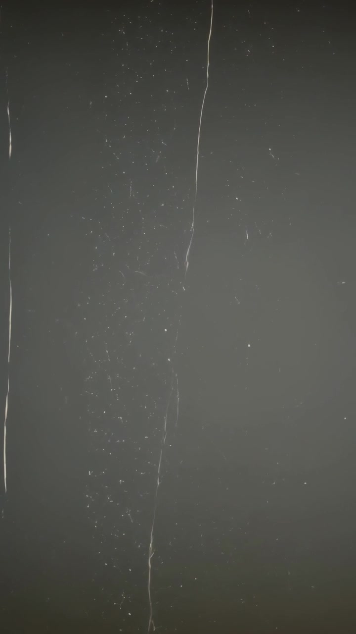 Vertical video: Showing narrow streak column with drifting specks as frames advance on gray pane