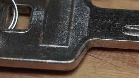 close-up of a shabby silver key to a blue keychain on a wooden table.