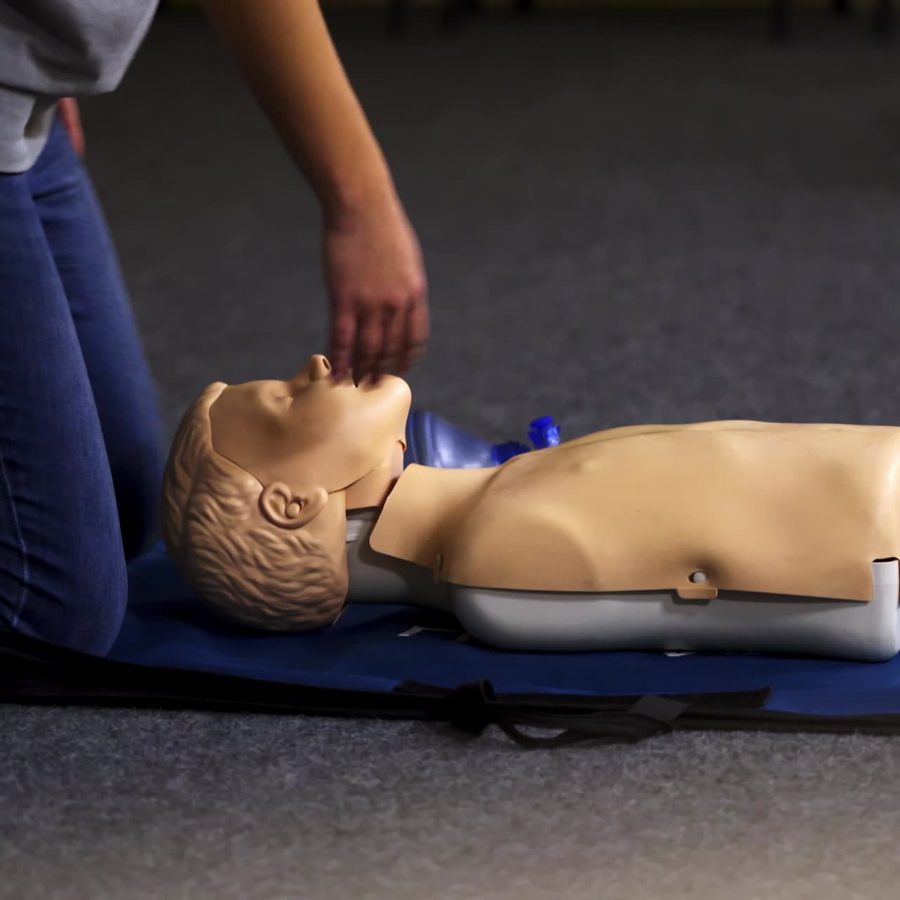 Medical training on a dummy. Instructor and practitioner near the mannequin. Practical exercise with breathing apparatus for giving first aid