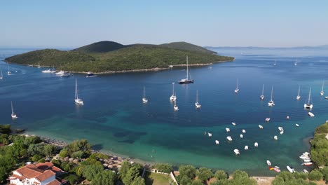 syvota coastal village with boats, blue ionian sea and green island in epirus, greece mainland - aerial