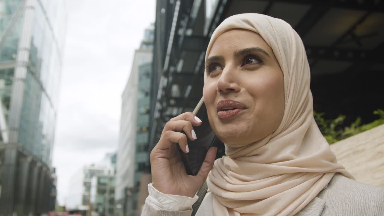 мусульманская бизнесменка на мобильном телефоне, стоящая перед офисом в городе 7