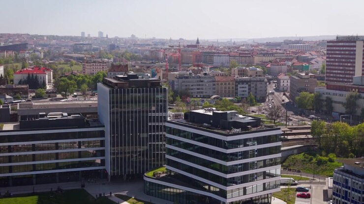 Vista aérea cinematográfica de edifícios de escritórios modernos e da área da estação de trem de Holesovice com o horizonte da cidade de Praga e a Torre Zizkov em um dia ensolarado