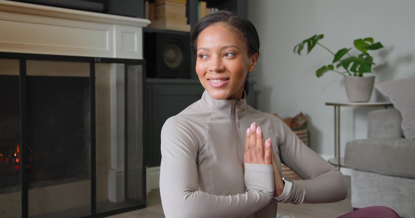 African American woman starting prayer, meditating, rotating torso on yoga mat at home in zip top