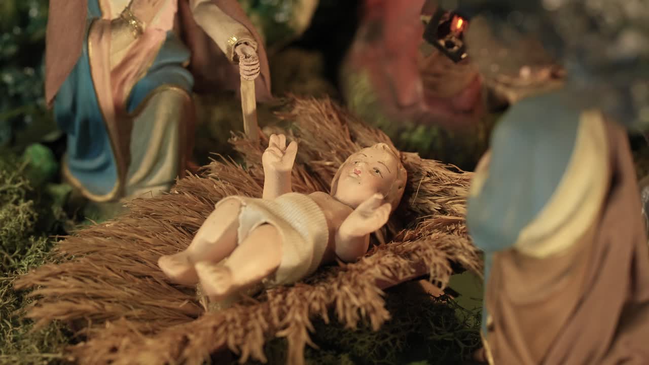 close up de la estatuilla del bebé jesús acostado en un pesebre en una escena de la natividad en movimiento