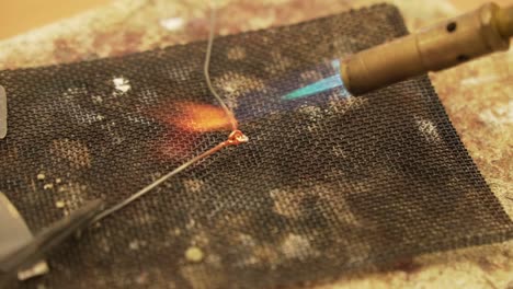 soldering metal wires with butane gas flame burner - close up shot in slow motion