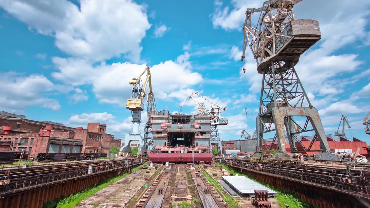 Costruzione della nave nel cantiere navale timelapse con gru. Cielo blu nuvoloso.