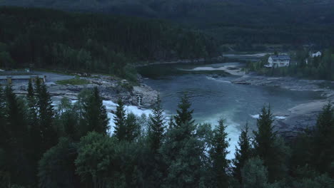 revealing a powerful waterfall and a river behind some treetops