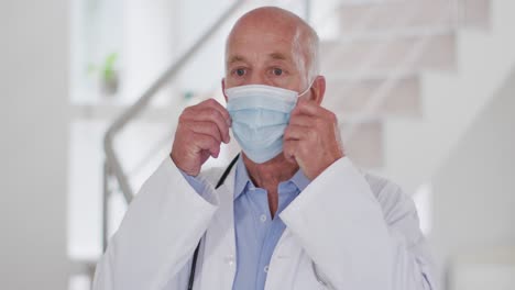 portrait of senior caucasian male doctor wearing face mask looking at camera