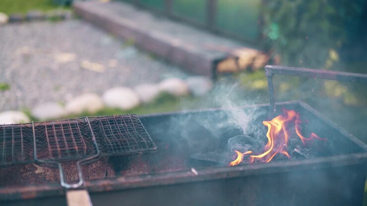Close-up man prepares the coals in the grill stirs them with a stick