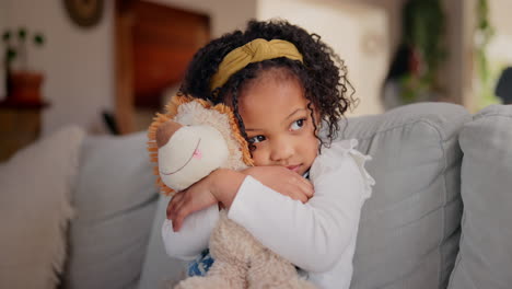 una niña abrazando a un león de peluche en el sofá
