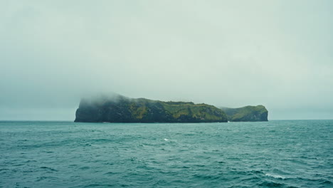 small rocky island in the middle of the north atlantic ocean on a misty cloudy weather