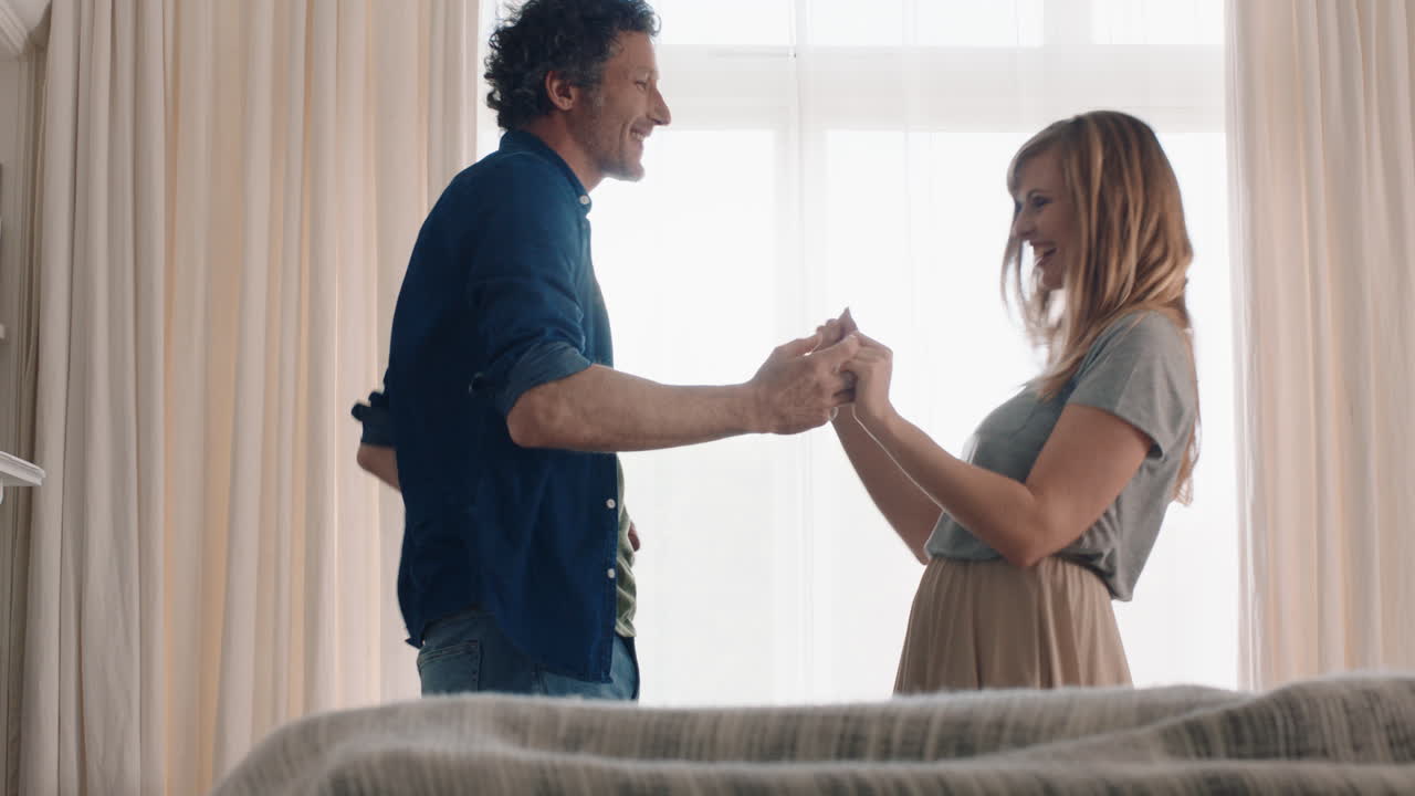 una pareja joven feliz bailando juntos en casa celebrando divirtiéndose el fin de semana sonriendo disfrutando de un baile divertido en la sala de estar celebrando una relación exitosa imágenes en 4k