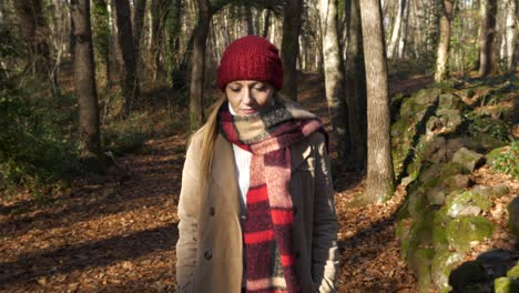 woman in red hat and scarf enjoys nature walk through autumn forest