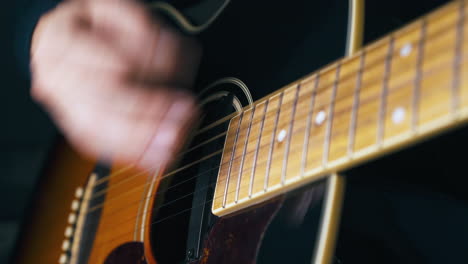 músico experto toca la guitarra acústica presionando las cuerdas
