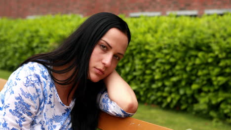 una morena triste pensando en un banco en el parque.