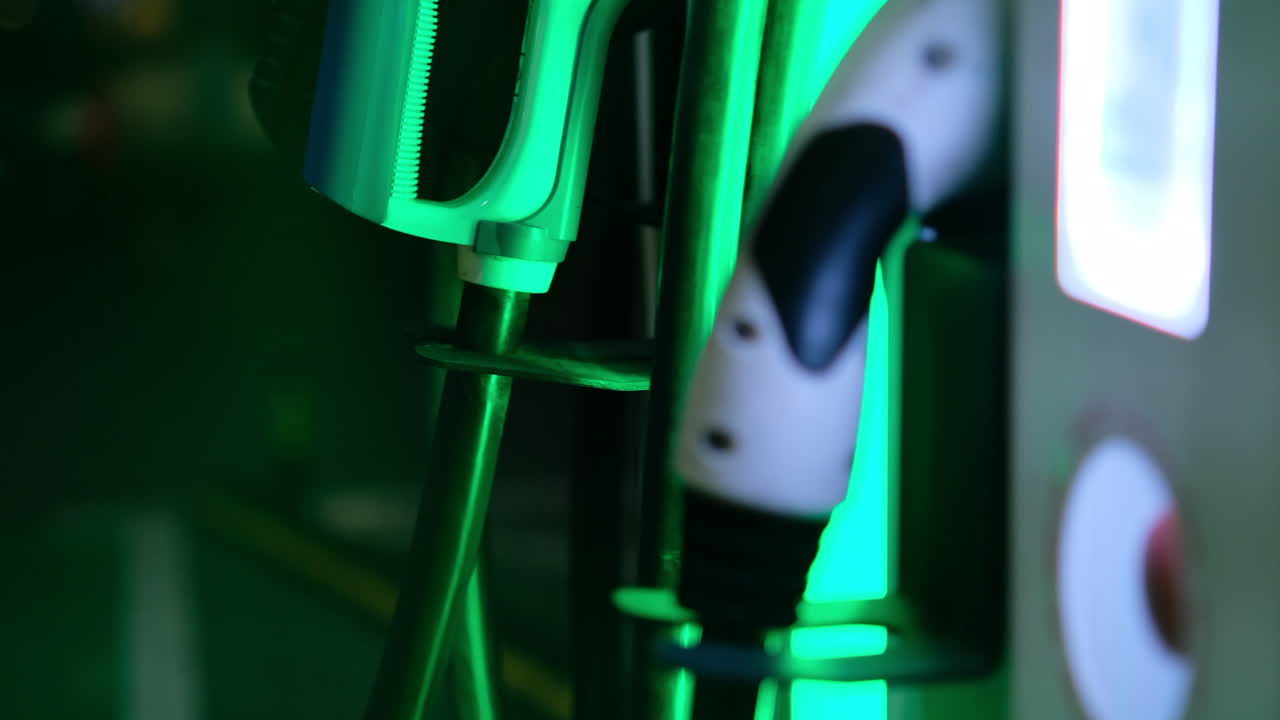 Green illuminated electric car charging point machine at night