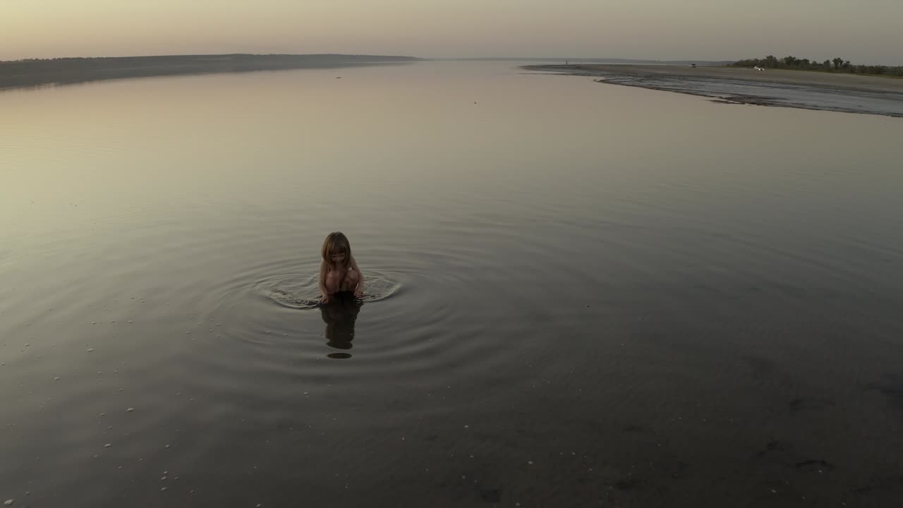 작은 소녀가 호수에서 목욕을 하고 있다