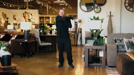 warehouse worker stretches while walking in a furniture store during a tracking shot