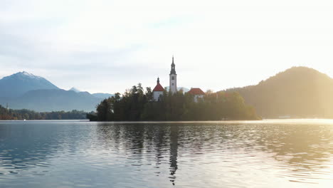 Epic-cinematic-drone-shot-of-the-sunset-and-the-the-Pilgrimage-Church-of-the-Assumption-of-Mary,-Slovenia