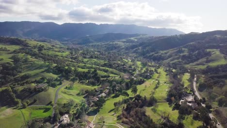 Country-side-lush-green-mountains,-covered-with-trees,-under-a-blue-sky-with-clouds