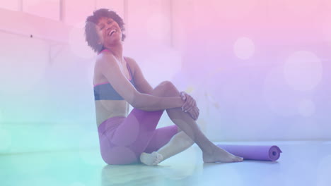 sitting on floor with yoga mat, woman smiling over pastel bokeh animation