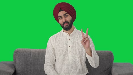 hombre indio sikh feliz mostrando el signo de la victoria pantalla verde
