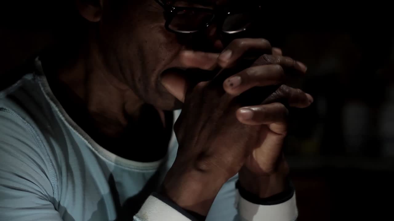 hombre rezando a dios con las manos juntas sobre fondo negro almacen de metraje de video