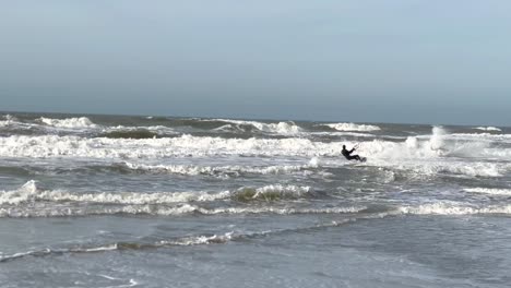 Surfista-De-Cometas-Desde-La-Costa-Con-Una-Tabla-Hacia-Las-Olas-Del-Océano-Y-Saltando-Al-Cielo---En-Tiempo-Real