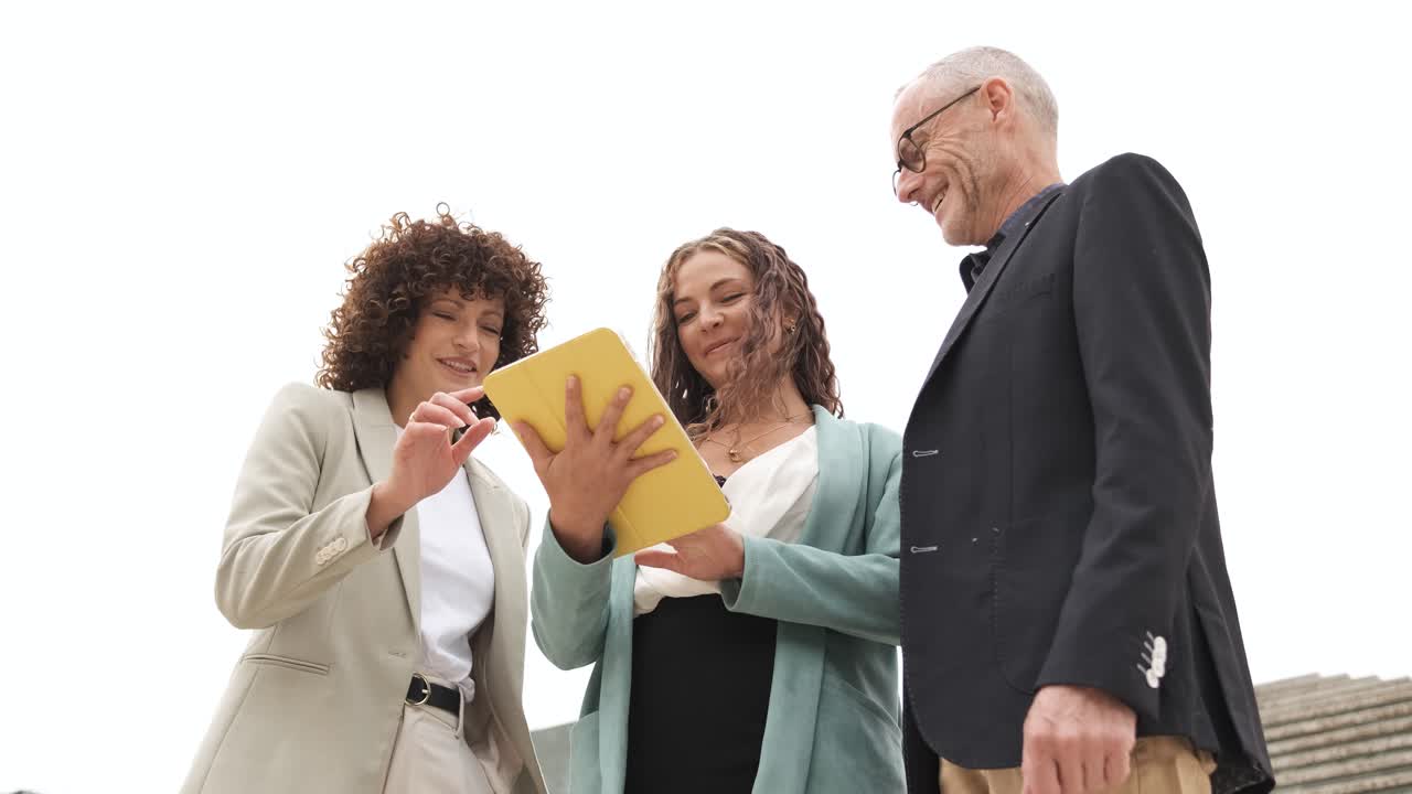 Business colleagues with tablet discussing ideas outdoors