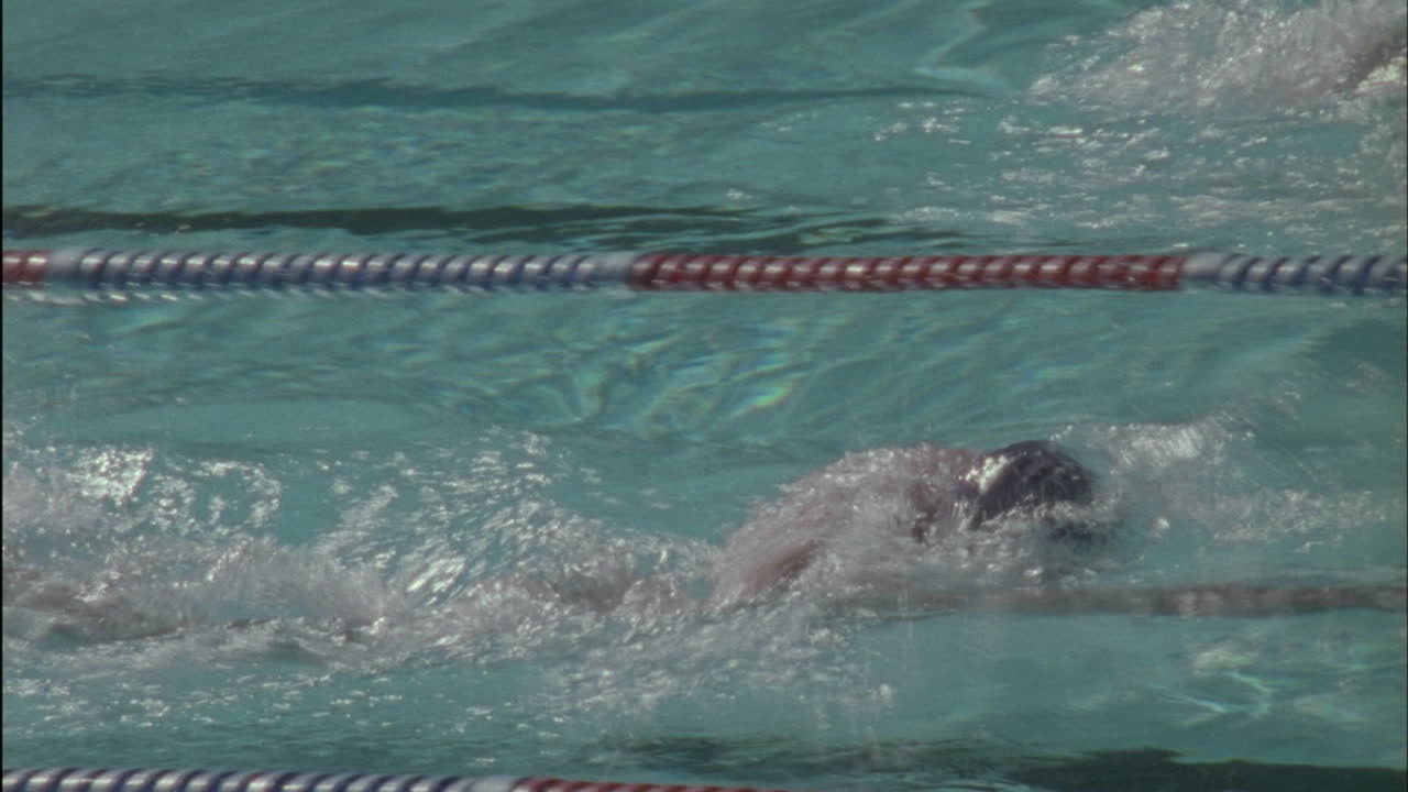 Male swimmers reach the edge turn over and start swimming back