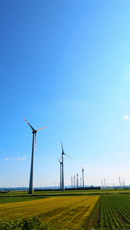 wind turbines stand tall in green fields. tall wind turbines tower above lush green fields under a clear blue sky on a sunny day