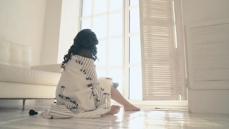 pretty girl covers herself with plaid on floor backside view