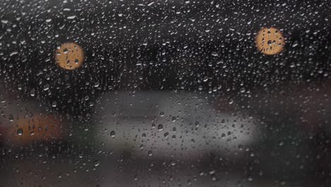 Primer-Plano-De-Gotas-De-Lluvia-Con-Automóviles-Pasando-Al-Fondo