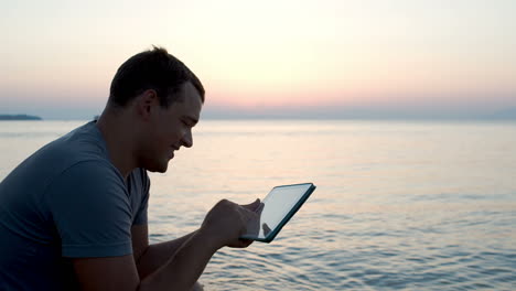 joven junto al mar escribiendo un mensaje en un bloc