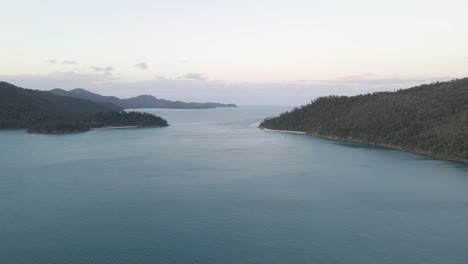 secluded anchorage with densely forested hills at dusk