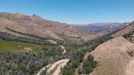 Vista-Aérea-De-Un-Sinuoso-Camino-De-Tierra-A-Través-De-Las-Montañas