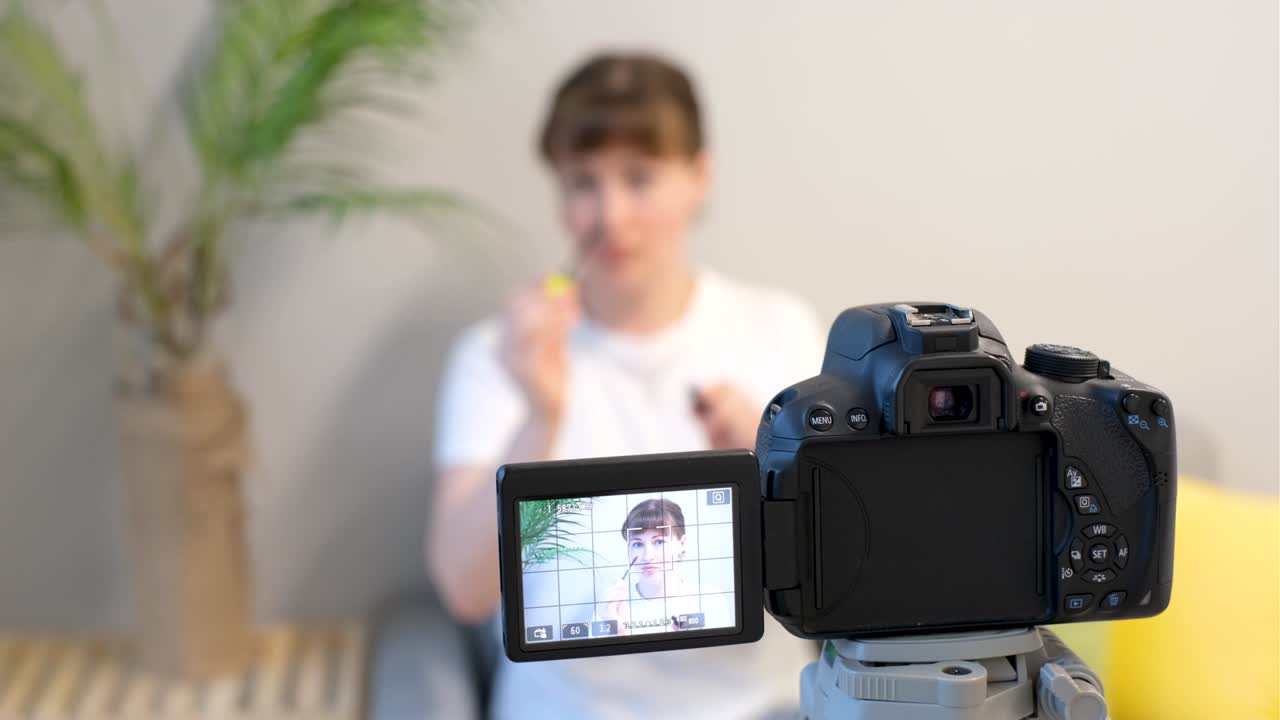 Young woman blogger recording video on camera closeup front view, selective focus.