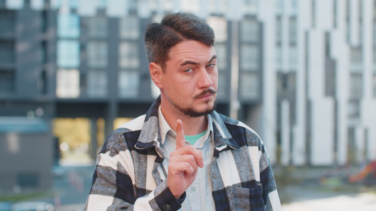 hombre caucásico presiona el dedo índice a los labios hace silencio silencio signo de gesto en la calle del centro de la ciudad